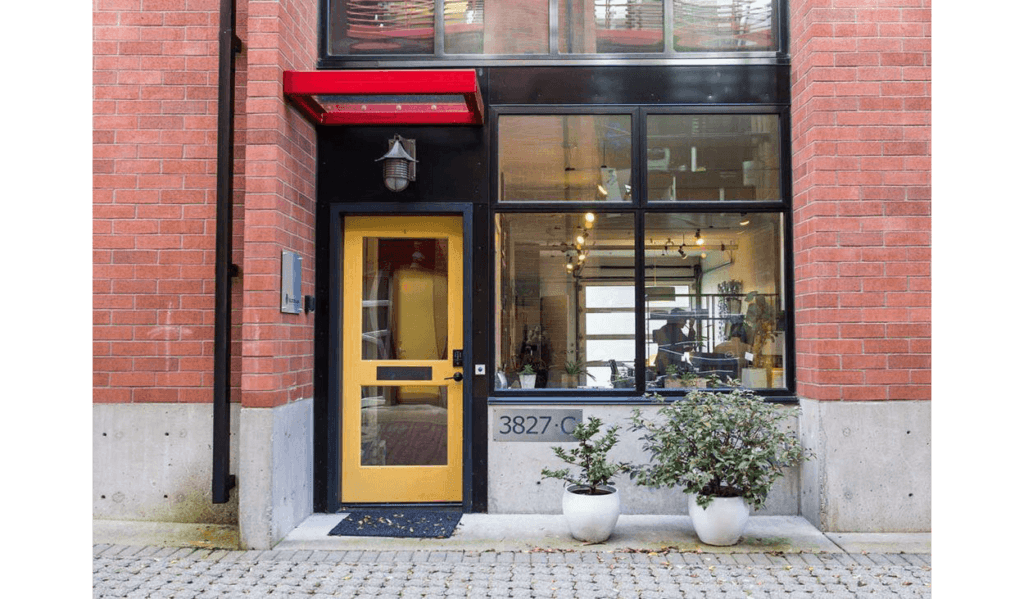 office building exterior with yellow door and two plants