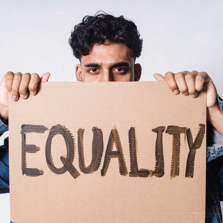 a man holding a cardboard sign with the word equality written on it
